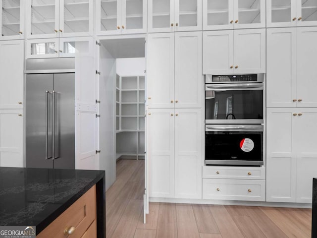 kitchen with dark stone countertops, white cabinetry, and stainless steel appliances