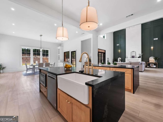 kitchen featuring sink, stainless steel dishwasher, pendant lighting, a spacious island, and light brown cabinetry