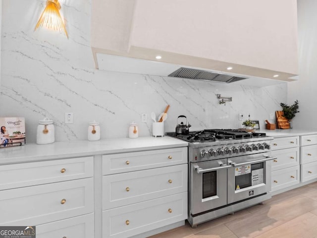 kitchen with double oven range, white cabinetry, and tasteful backsplash