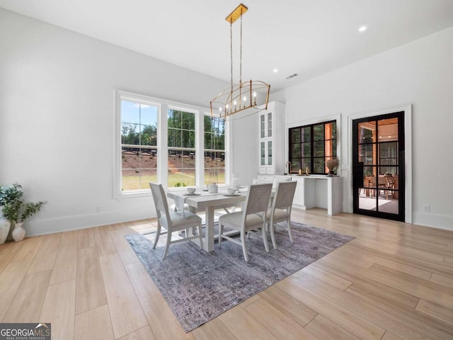 dining room with light hardwood / wood-style floors and an inviting chandelier