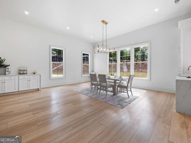 dining area with light hardwood / wood-style floors and an inviting chandelier