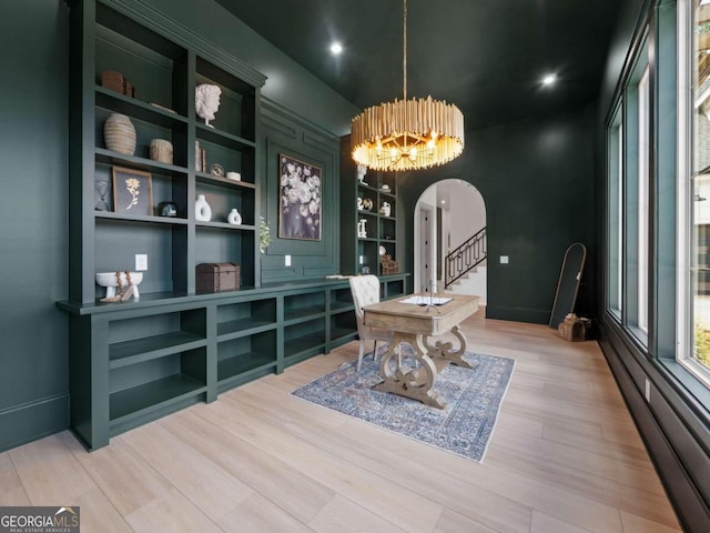 dining area with built in shelves, light hardwood / wood-style floors, a chandelier, and a baseboard heating unit