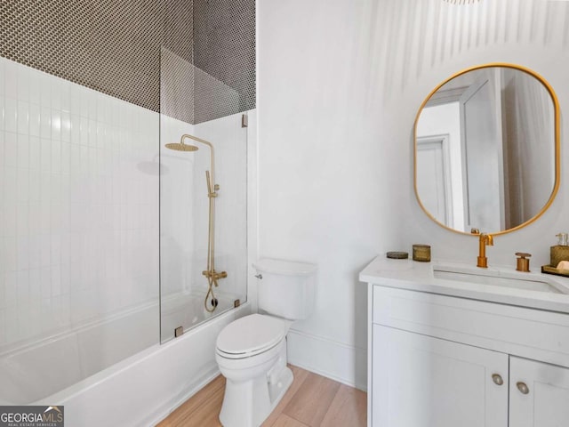 full bathroom featuring hardwood / wood-style floors, vanity, toilet, and bath / shower combo with glass door