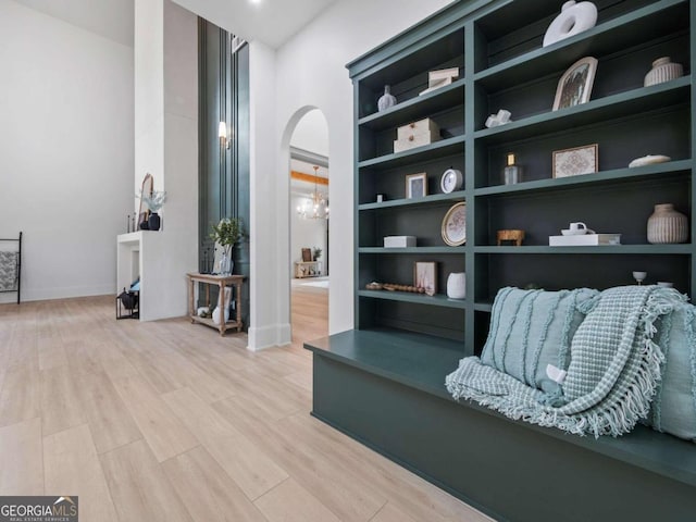 sitting room featuring built in shelves and light hardwood / wood-style flooring