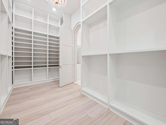 spacious closet with a chandelier and light hardwood / wood-style floors