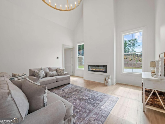 living room featuring high vaulted ceiling, light wood-type flooring, and an inviting chandelier