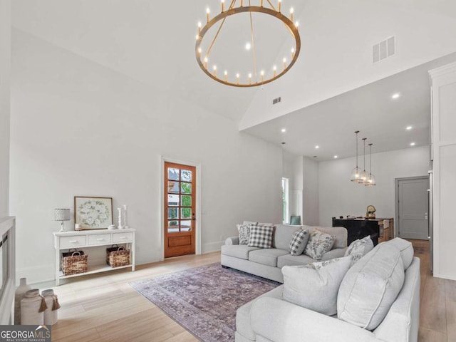 living room featuring a chandelier, light wood-type flooring, and high vaulted ceiling