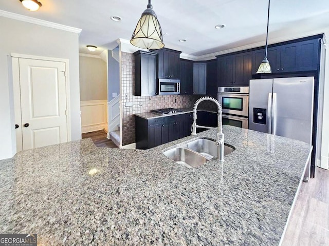 kitchen with sink, crown molding, hanging light fixtures, appliances with stainless steel finishes, and light stone counters