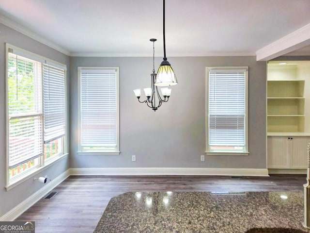 unfurnished dining area featuring dark hardwood / wood-style floors, an inviting chandelier, and ornamental molding