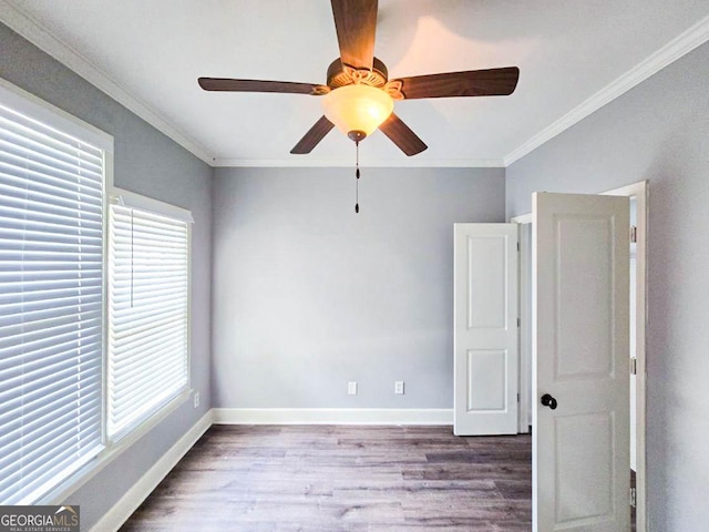 empty room with a healthy amount of sunlight, ornamental molding, and hardwood / wood-style flooring