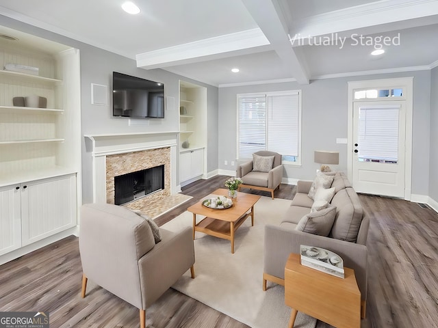 living room with beam ceiling, a fireplace, built in features, hardwood / wood-style flooring, and crown molding