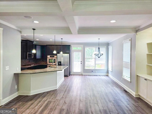 kitchen featuring dark stone countertops, kitchen peninsula, decorative backsplash, stainless steel appliances, and dark hardwood / wood-style flooring