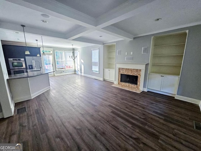 unfurnished living room with a high end fireplace, dark hardwood / wood-style flooring, beamed ceiling, sink, and built in features