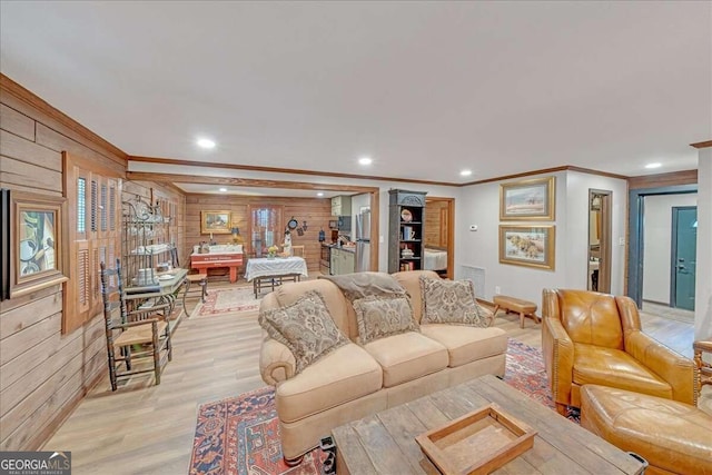 living room featuring wood walls, crown molding, and light wood-type flooring