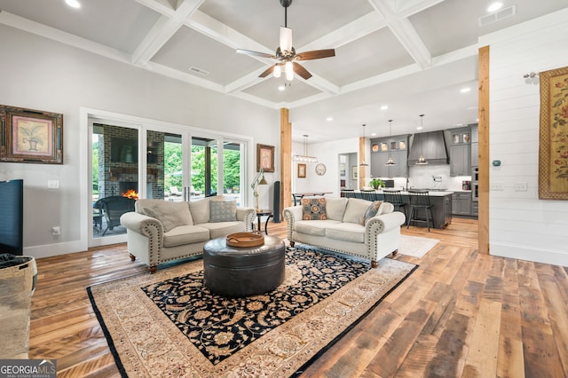 living room with beam ceiling, light hardwood / wood-style floors, coffered ceiling, and ceiling fan