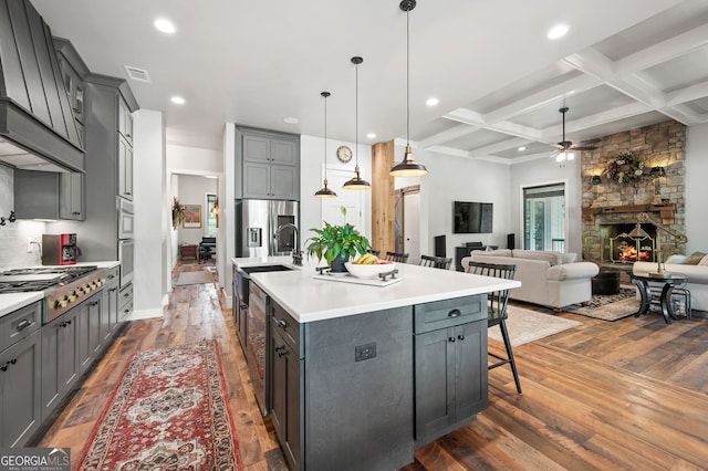 kitchen featuring beam ceiling, premium range hood, dark hardwood / wood-style floors, coffered ceiling, and a stone fireplace