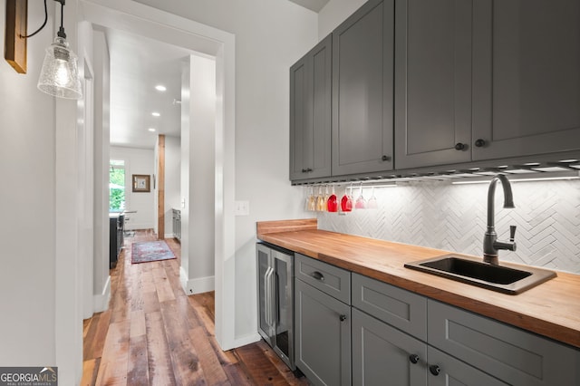 kitchen featuring decorative backsplash, hardwood / wood-style flooring, butcher block countertops, and sink