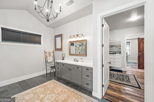 bathroom featuring vanity, an inviting chandelier, lofted ceiling, and tile patterned flooring