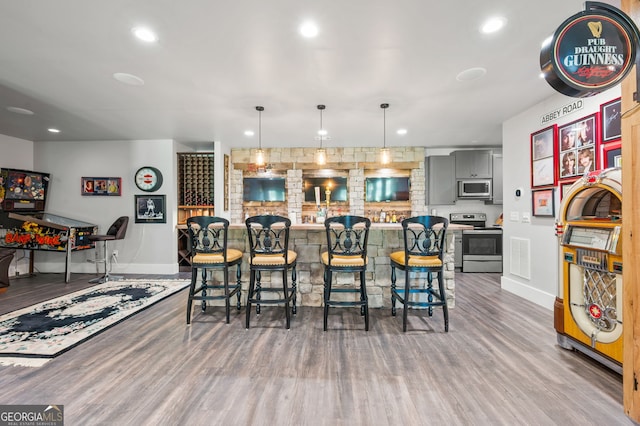 interior space with a kitchen bar, wood-type flooring, and stainless steel appliances