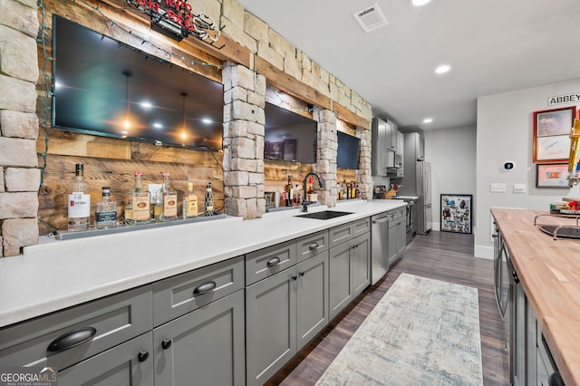 kitchen featuring wooden counters, dark wood-type flooring, appliances with stainless steel finishes, and sink