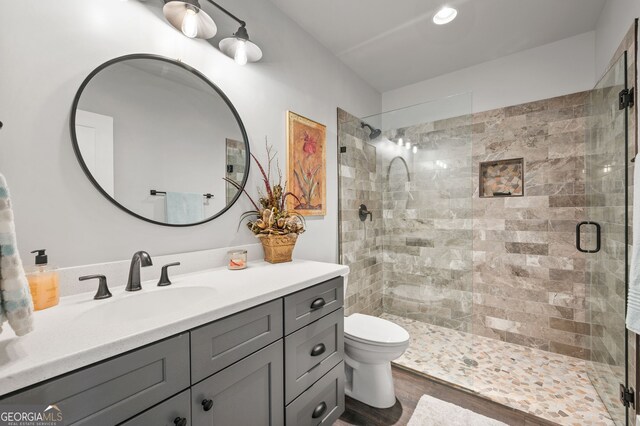 bathroom featuring vanity, a shower with door, wood-type flooring, and toilet