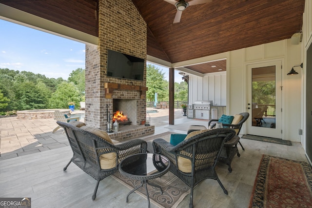 view of patio featuring an outdoor brick fireplace, a grill, exterior kitchen, and ceiling fan