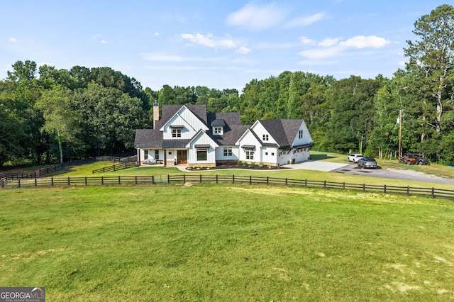 view of front of house featuring a garage, a front lawn, and a rural view