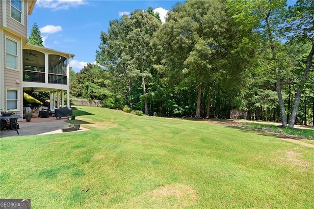 view of yard with ceiling fan, a sunroom, and a patio area