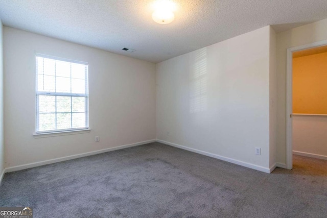 carpeted empty room featuring a textured ceiling