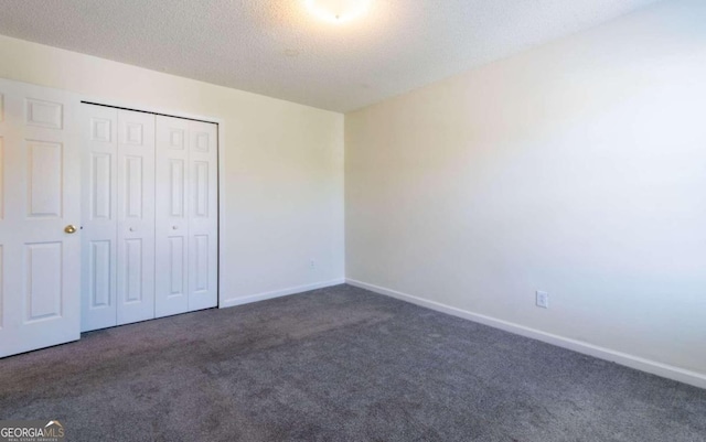 unfurnished bedroom featuring a textured ceiling, a closet, and dark carpet