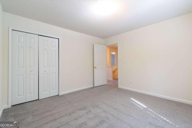 unfurnished bedroom featuring light colored carpet, a closet, and a textured ceiling