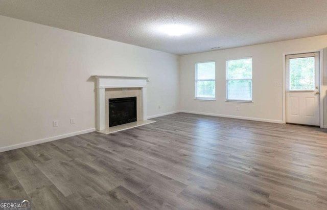 unfurnished living room featuring a premium fireplace, a textured ceiling, and hardwood / wood-style flooring