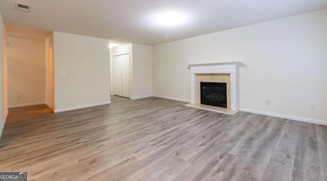 unfurnished living room featuring light wood-type flooring and a textured ceiling