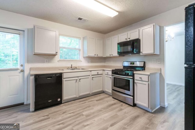 kitchen with sink, white cabinetry, black appliances, and a textured ceiling