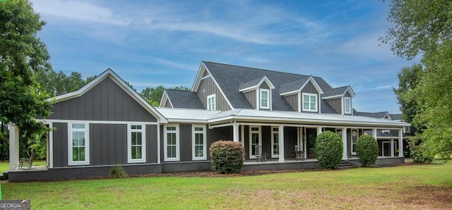 back of house featuring covered porch, board and batten siding, and a yard