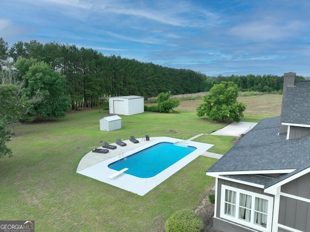 outdoor pool featuring an outbuilding, a lawn, a storage shed, a patio area, and a wooded view