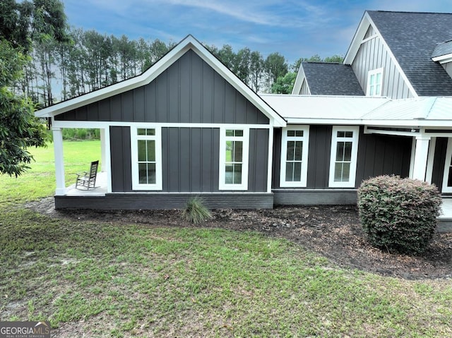 view of home's exterior with board and batten siding, roof with shingles, and a lawn