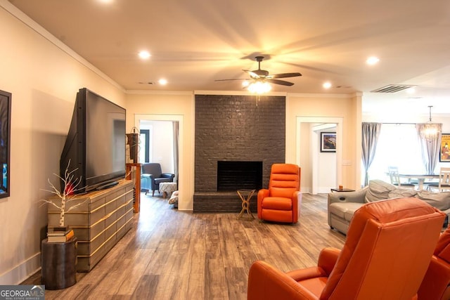 living area featuring visible vents, wood finished floors, crown molding, a fireplace, and recessed lighting