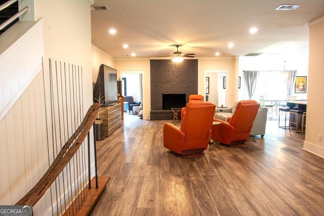 living area with a large fireplace, visible vents, and wood finished floors