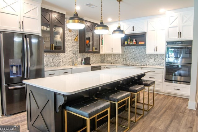 kitchen with stainless steel appliances, light countertops, glass insert cabinets, and a center island