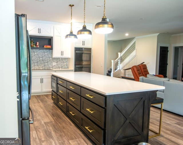 kitchen featuring decorative light fixtures, light countertops, double oven, open floor plan, and white cabinets