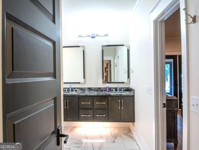 full bath with double vanity, marble finish floor, and a sink