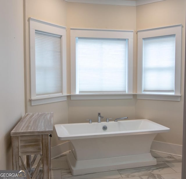 full bathroom featuring marble finish floor, baseboards, and a freestanding bath