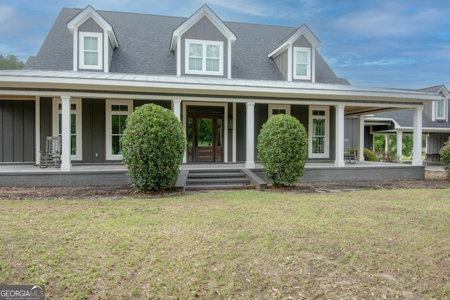 view of front of house featuring board and batten siding, a front yard, and roof with shingles