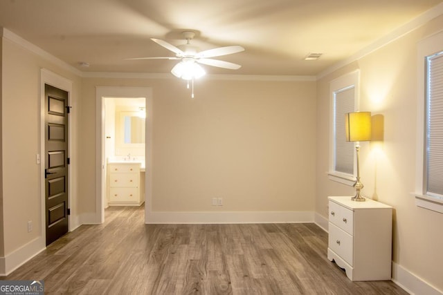 unfurnished bedroom with light wood-style flooring, visible vents, baseboards, and crown molding