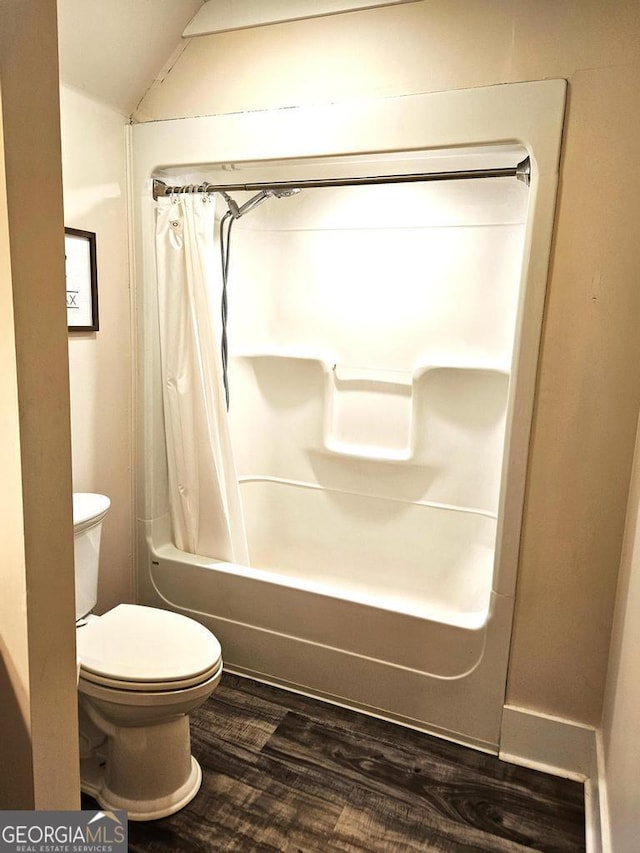 bathroom with vaulted ceiling, shower / bath combo with shower curtain, wood finished floors, and toilet