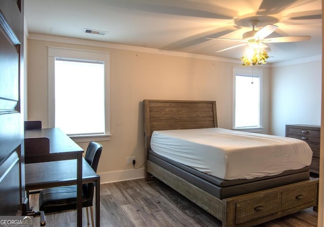 bedroom with ceiling fan, wood finished floors, visible vents, baseboards, and crown molding