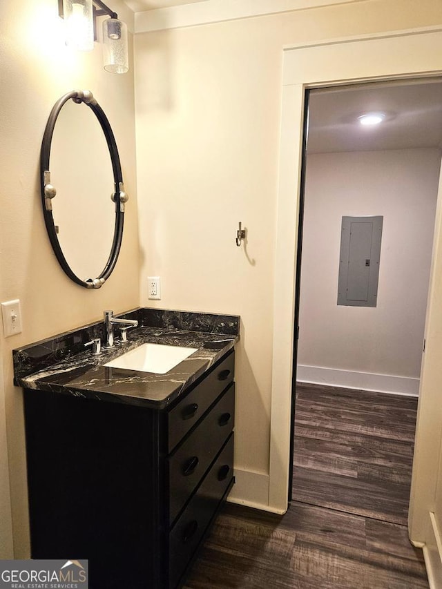 bathroom featuring wood finished floors, vanity, electric panel, and baseboards