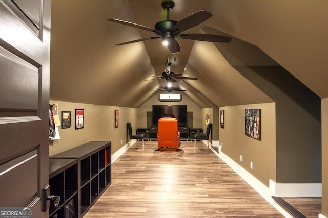 interior space featuring a ceiling fan, vaulted ceiling, light wood-style flooring, and baseboards