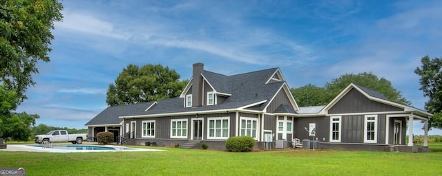 rear view of house featuring entry steps, a yard, and an outdoor pool